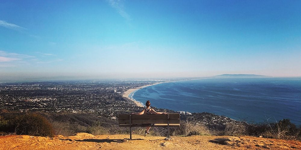 woman sitting on a park bench over looking Los Angeles