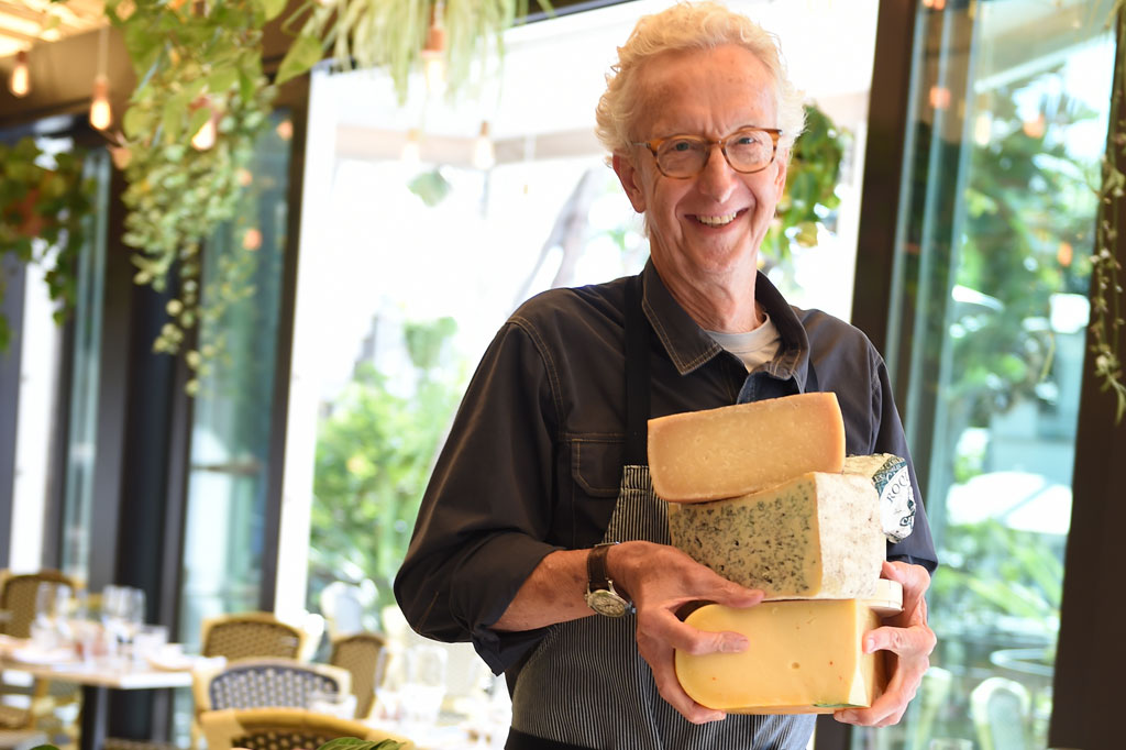 Eric holding a stack of different cheeses