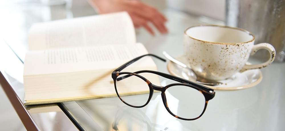 book, glasses, and tea cup on a glass table