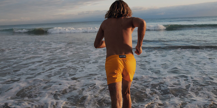 man running into the ocean on the beach