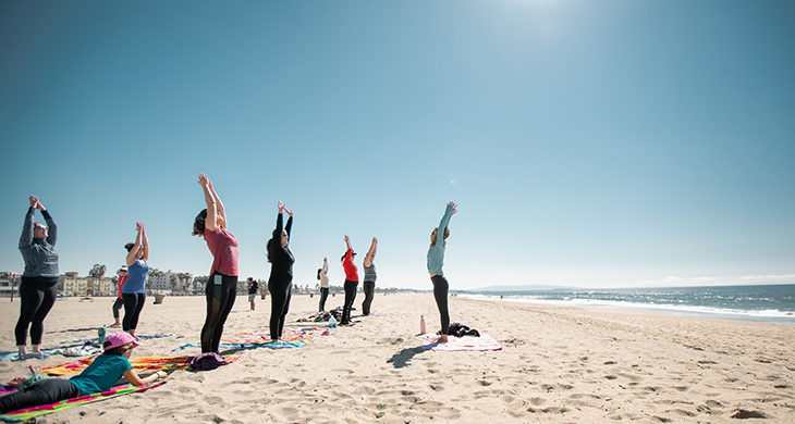 group doing yoga on the beach