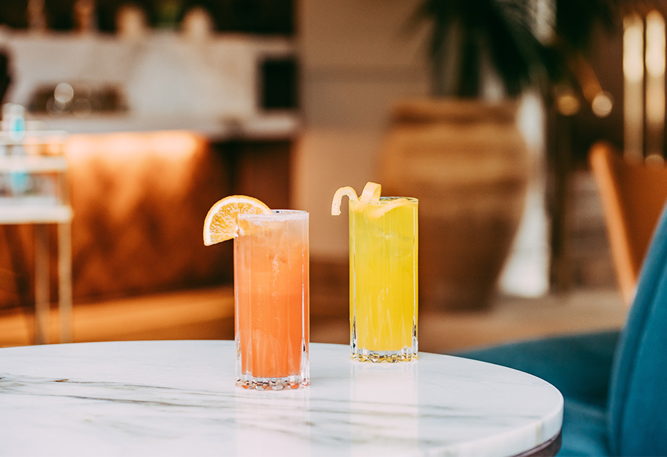 two bright cocktails on a marble table