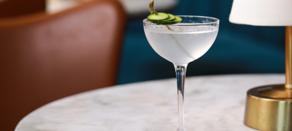 close up of a cocktail with cucumber garnish