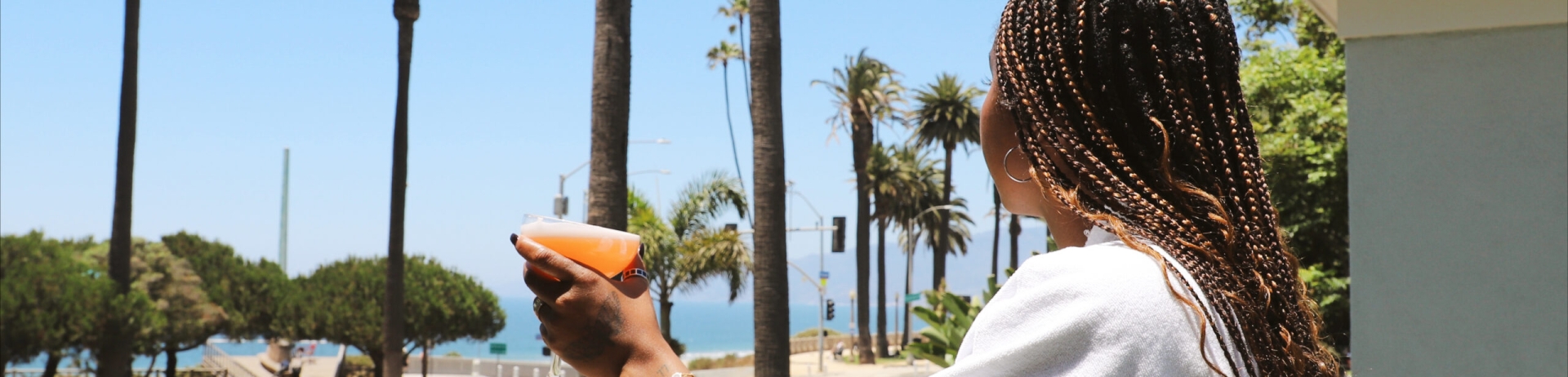 woman in bathrobe drinking a cocktail on a balcony