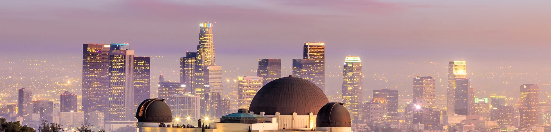 exterior shot of the griffith observatory with the city skyline in the background