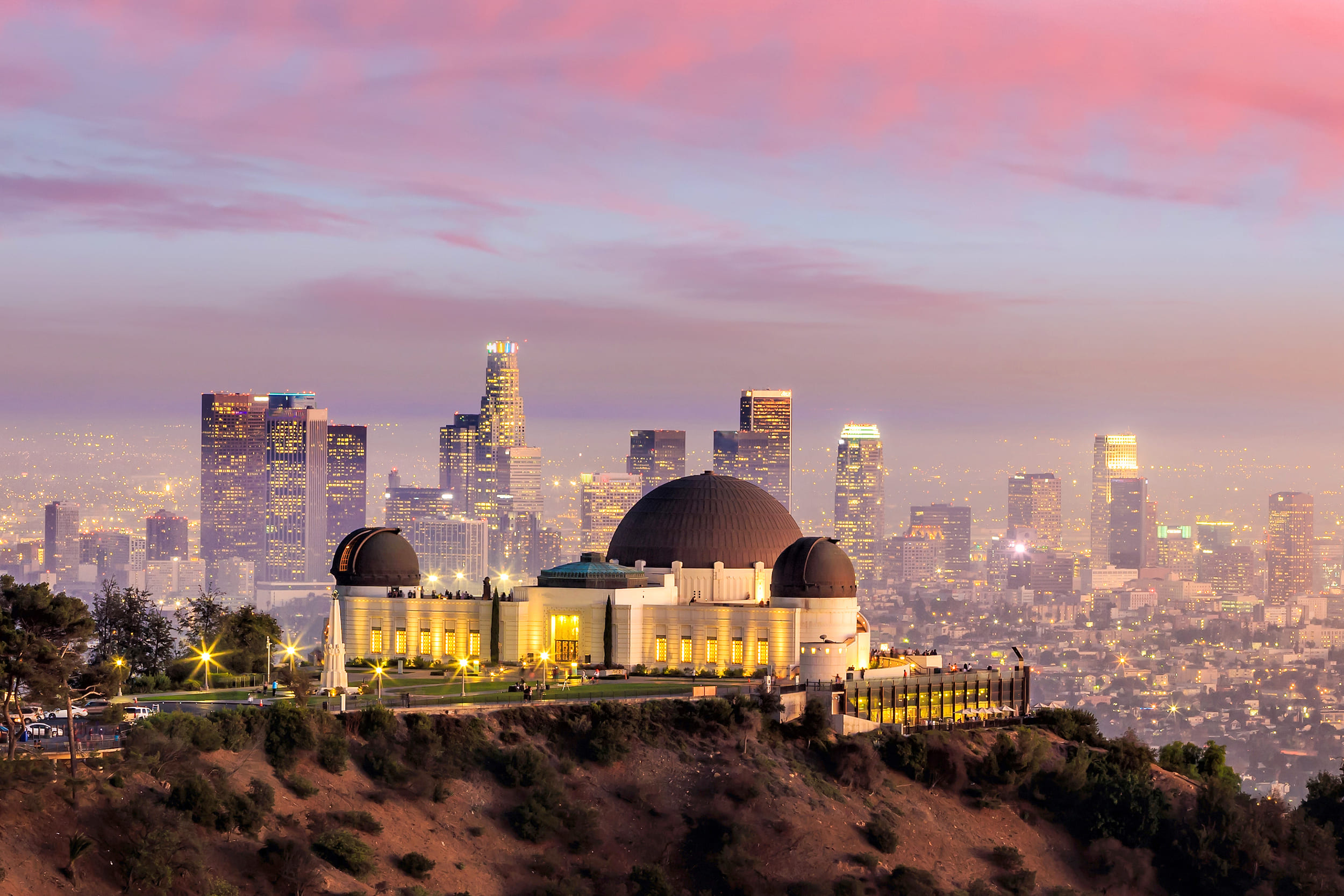 exterior shot of the griffith observatory with the city skyline in the background