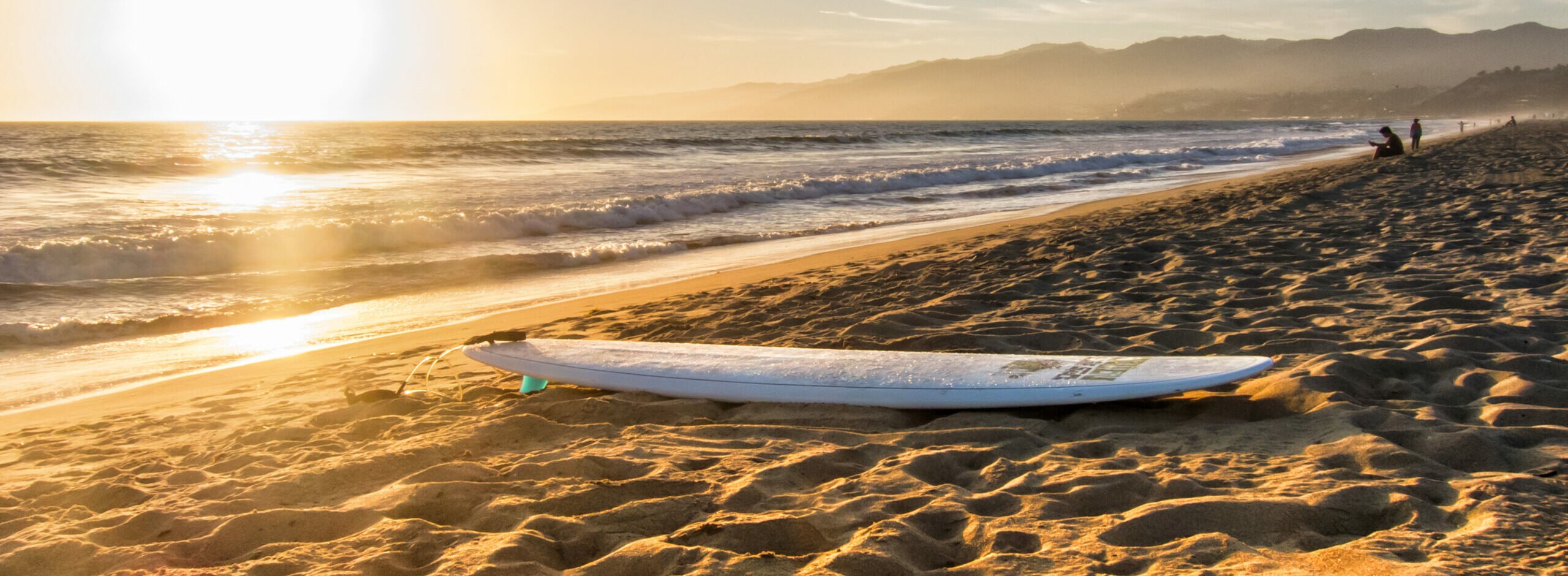 surfboard on the beach at sunset