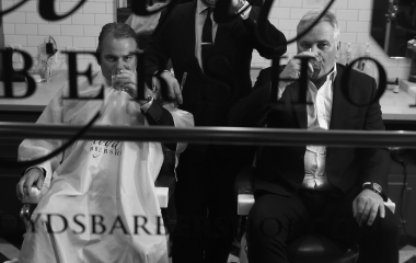 three men drinking in a bardershop through the glass