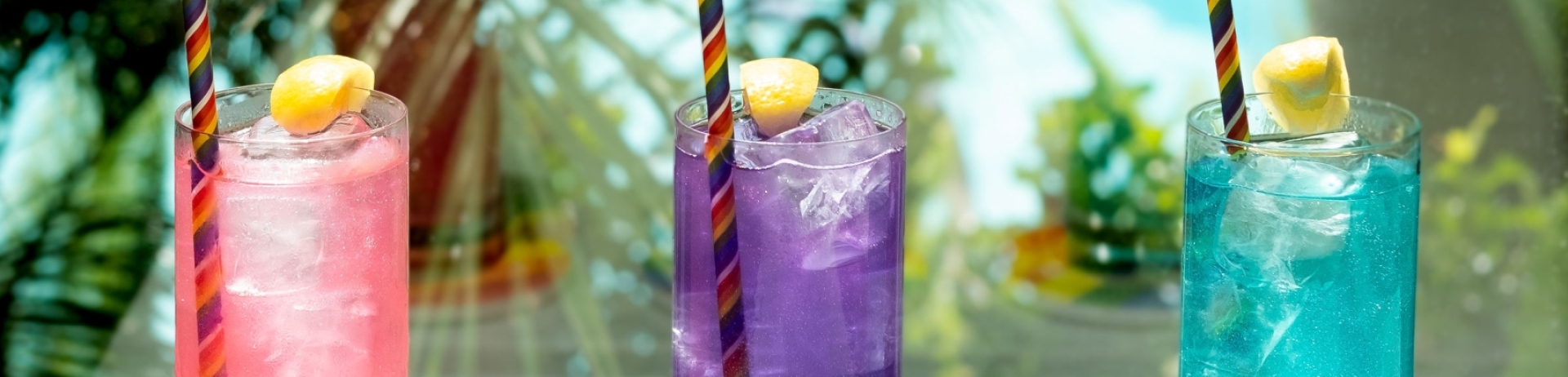 three cocktails with palm trees in the background