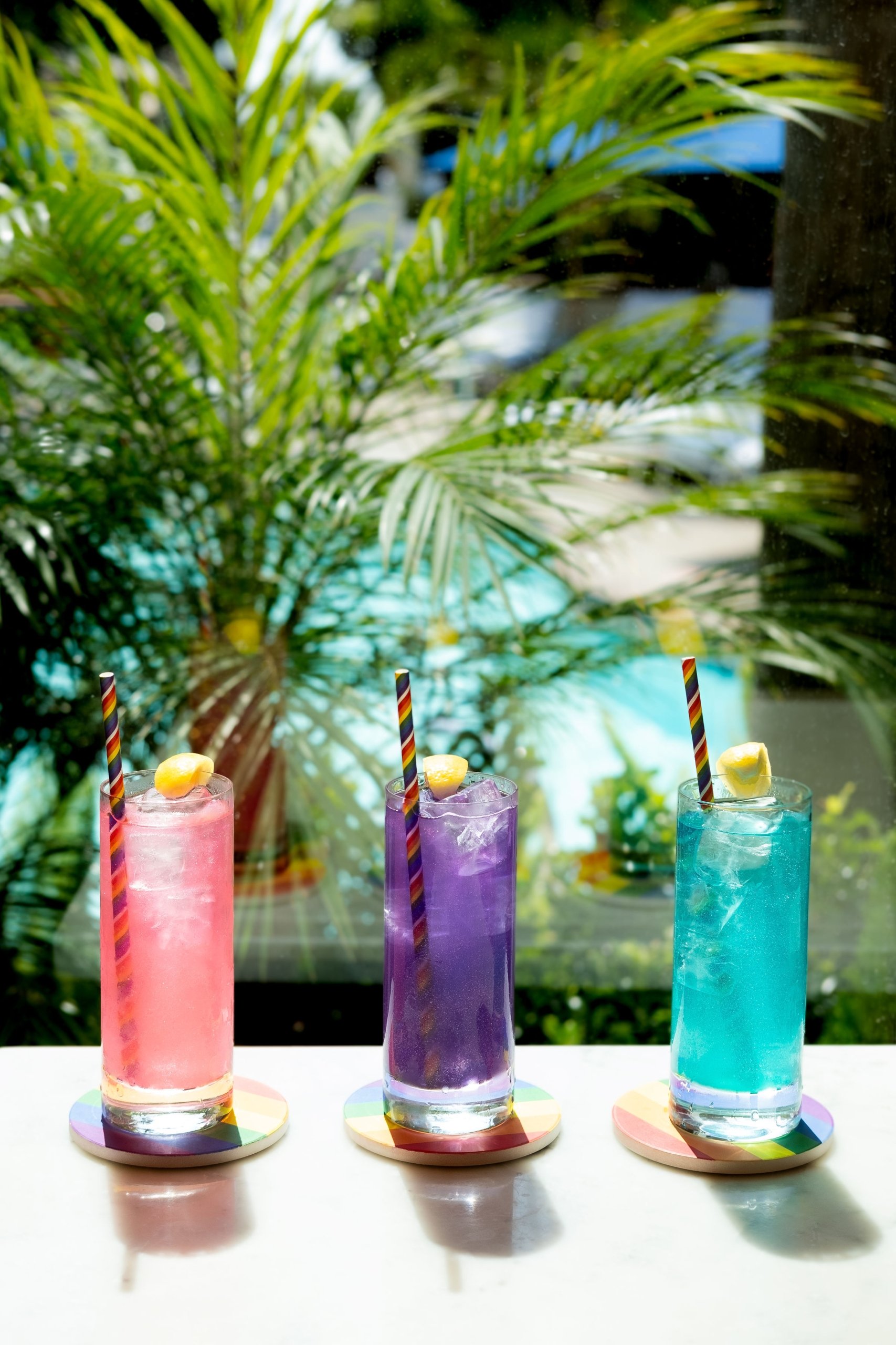 three cocktails with palm trees in the background